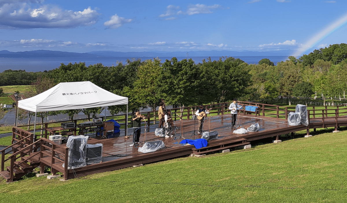 海をバックにした５人編成の弦楽器バンドによる演奏